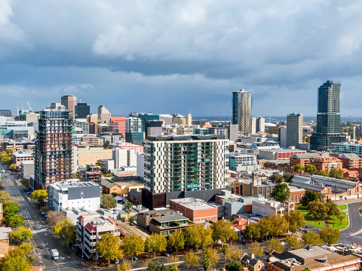 City skyline of South Australian city, Adelaide with tall buildings and trees in the foreground.